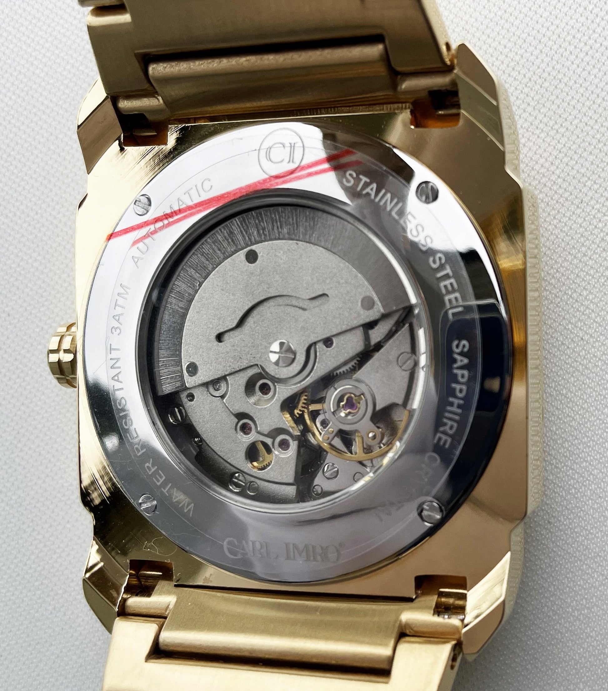 Gold watch with mechanical components on a gray background