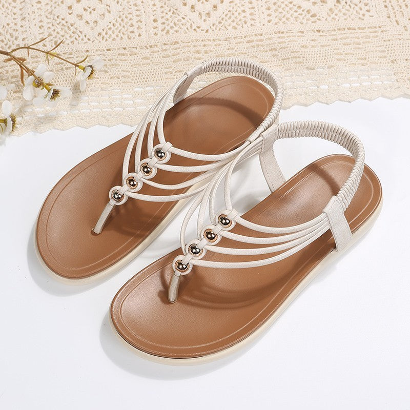 Pair of white sandals with brown soles on a light background