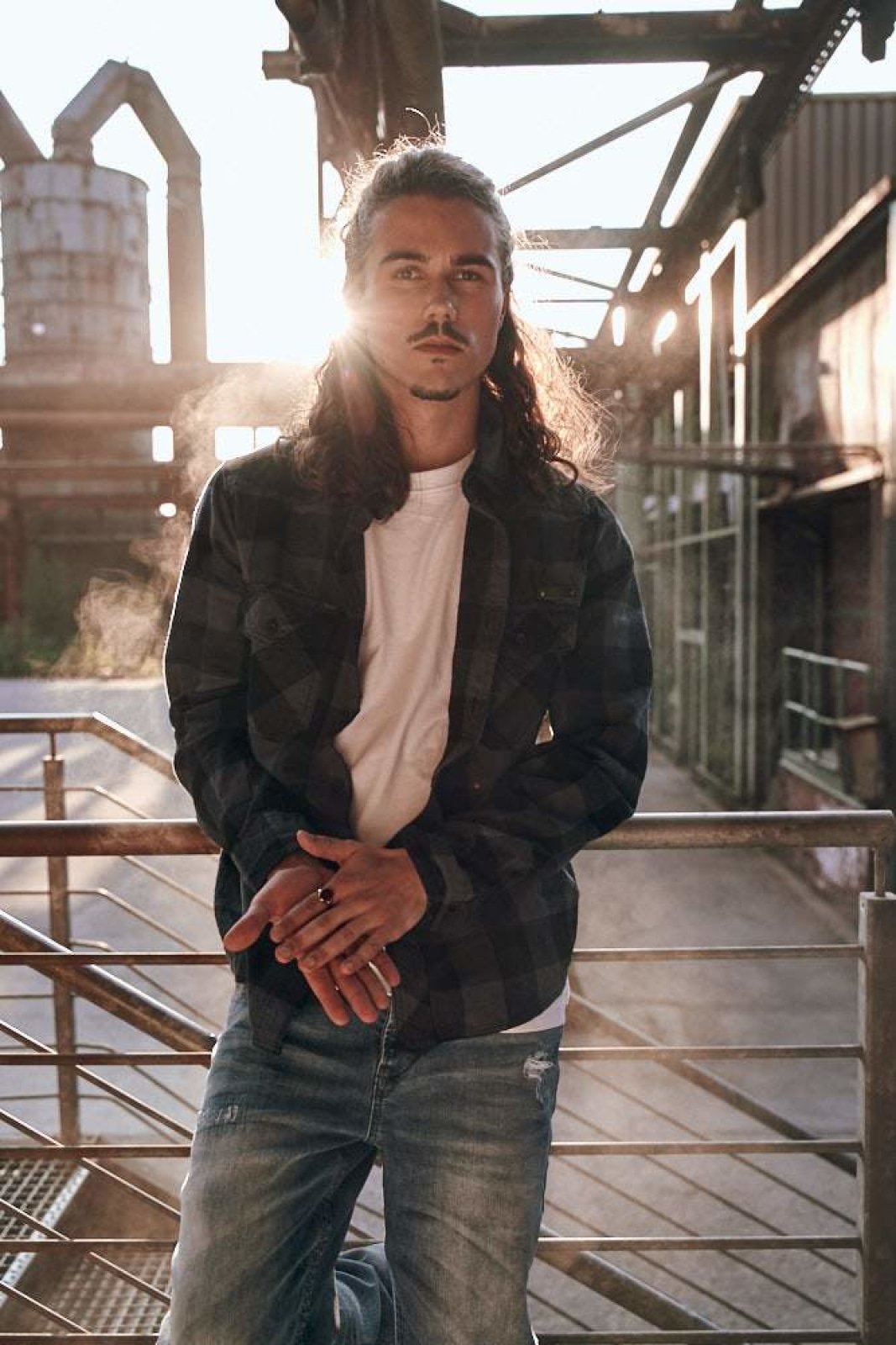 Man standing in an industrial setting with sunlight filtering through