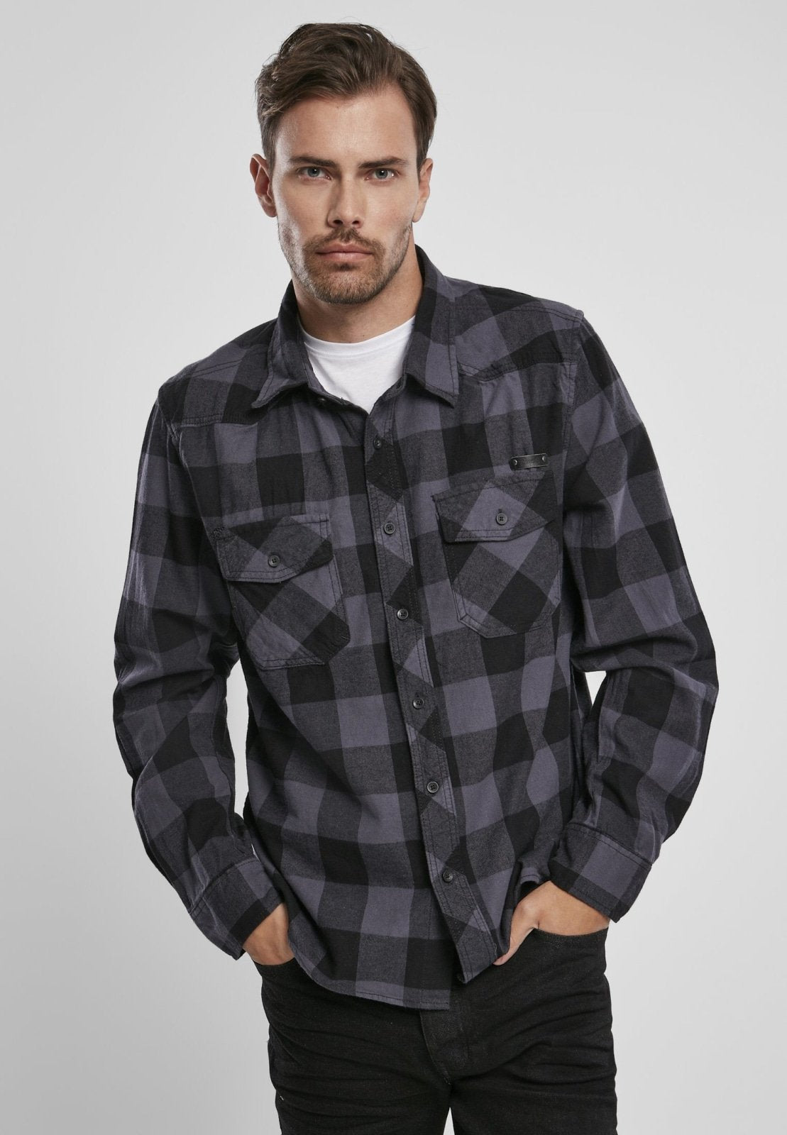 Man wearing a black and gray plaid shirt on a white background