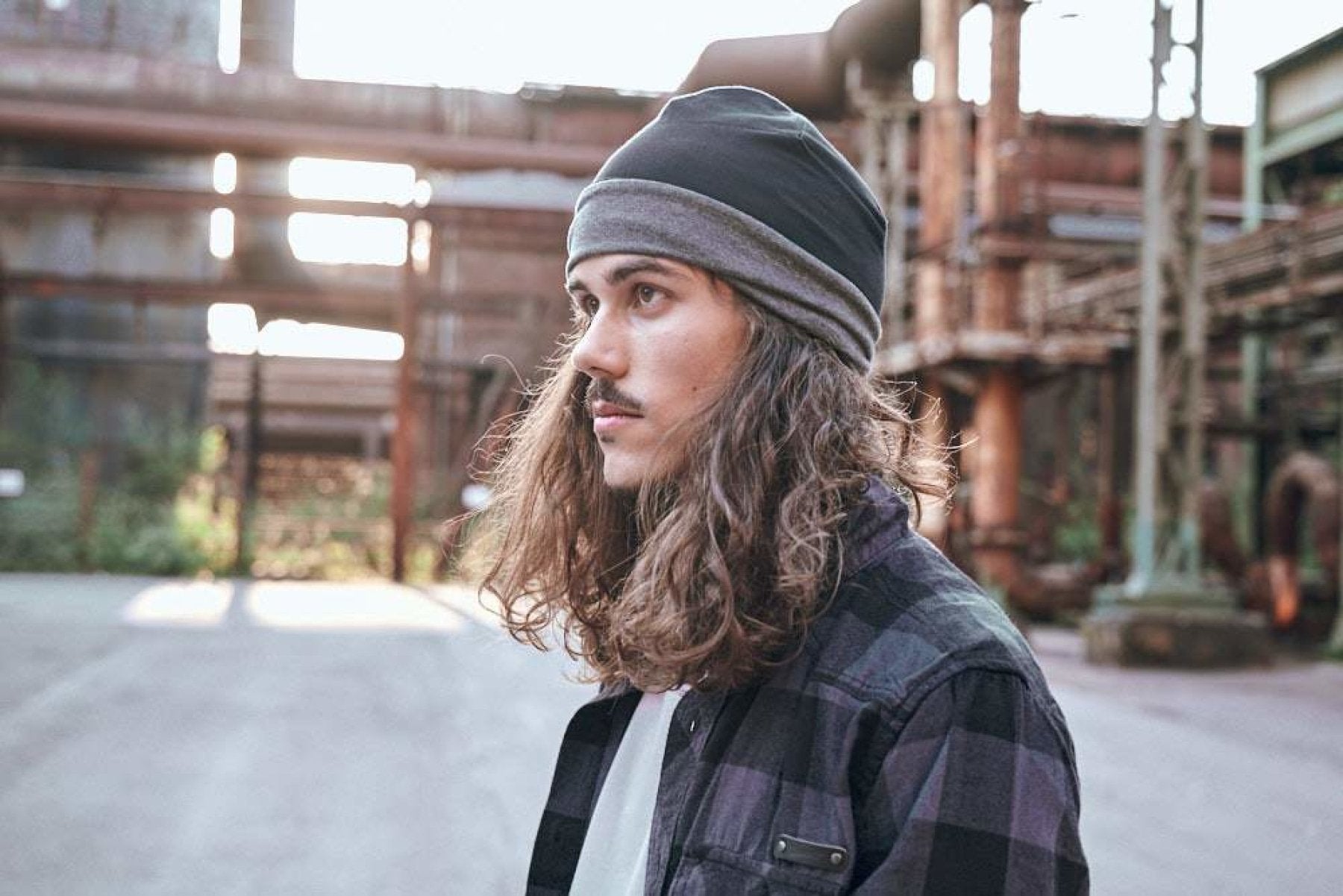 Person wearing a beanie and plaid shirt in an industrial setting