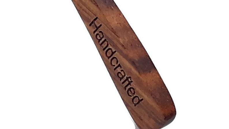 Wooden spoon with 'Handcrafted' engraving on a white background