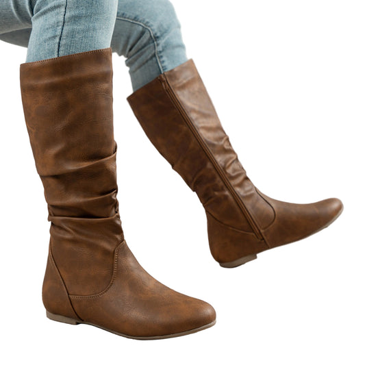 Brown knee-high boots worn with light blue jeans on a white background