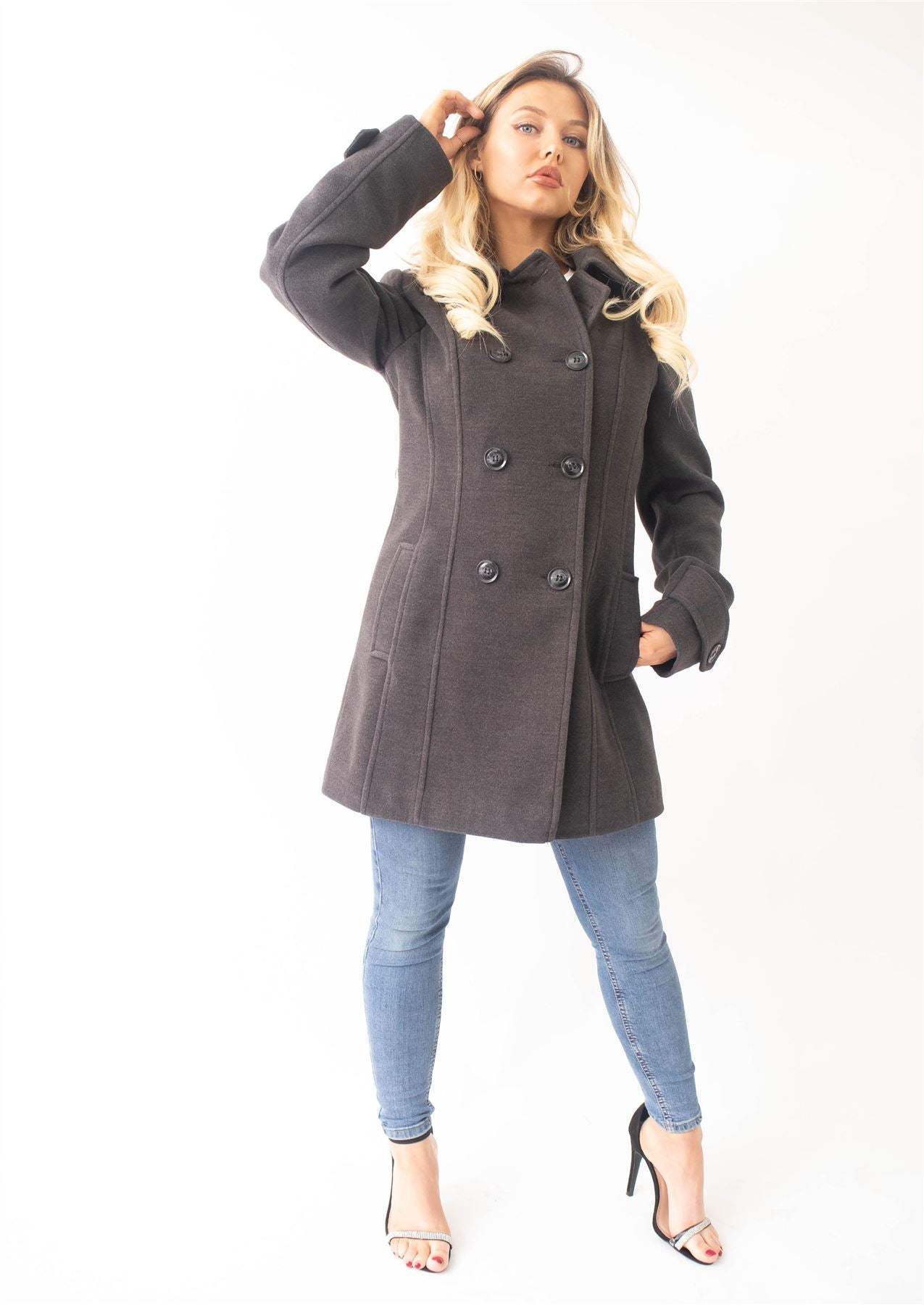 Woman wearing a gray coat and blue jeans on a white background