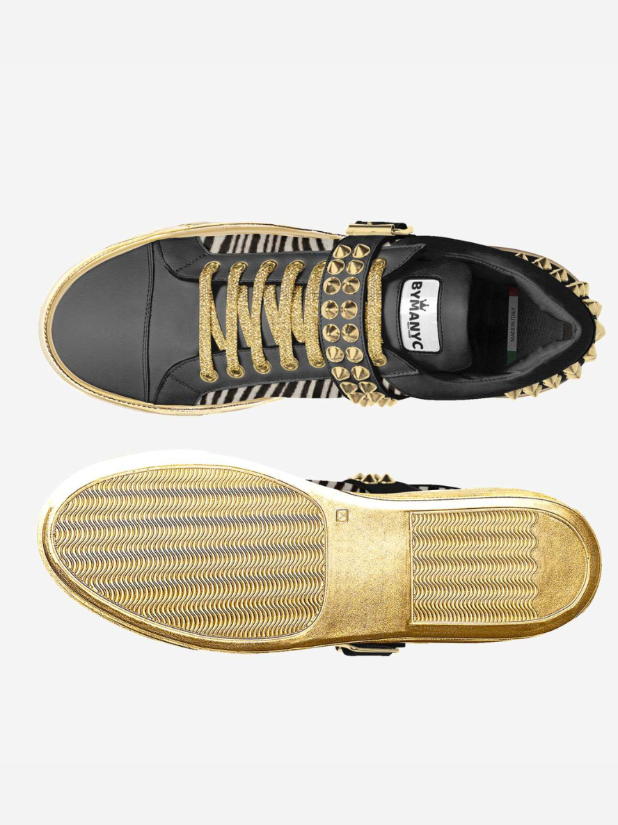 Black and gold sneaker with studded details on a white background