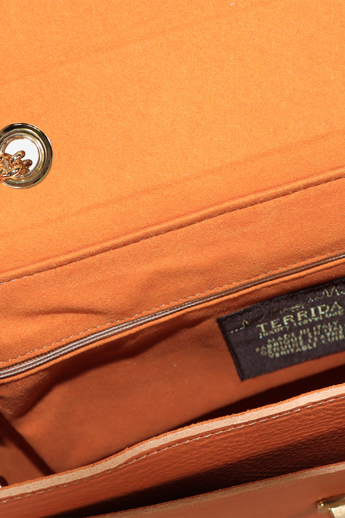 Close-up of an orange leather bag with a visible brand label.