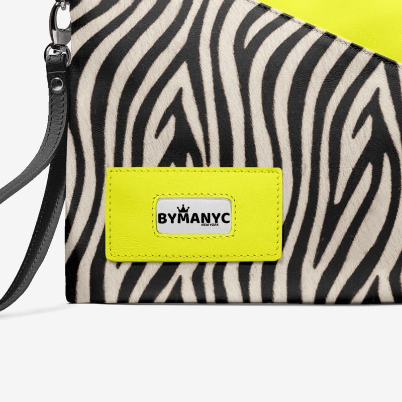Zebra patterned clutch with a bright yellow tag featuring 'BY MANYC' on a white background