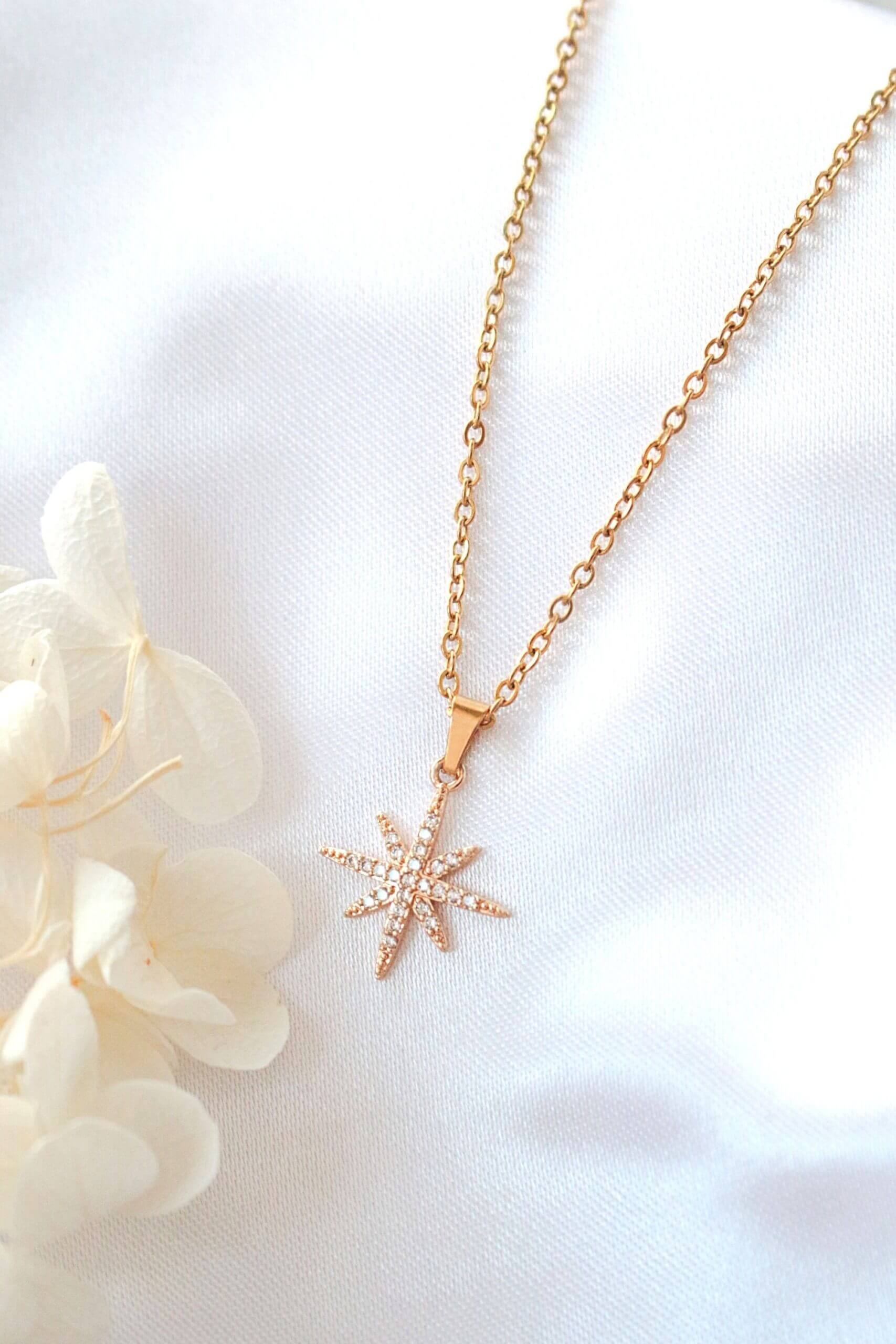 Gold starfish pendant necklace on a white background with delicate flowers.