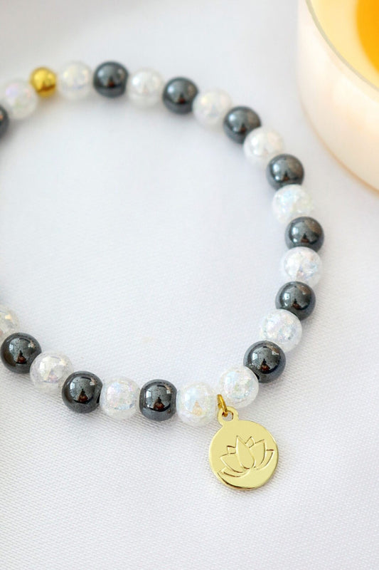 Bracelet with pearls, black beads, and a gold charm on a light background