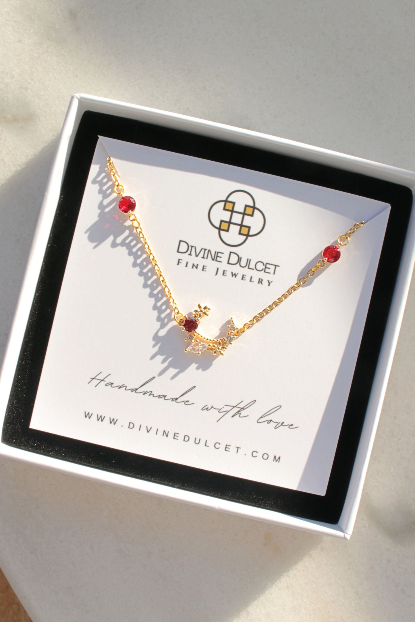 Gold necklace with red stones on a Divine Dulcet jewelry card.