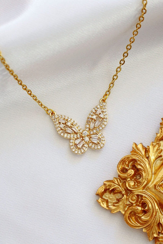 Gold butterfly necklace on a white background