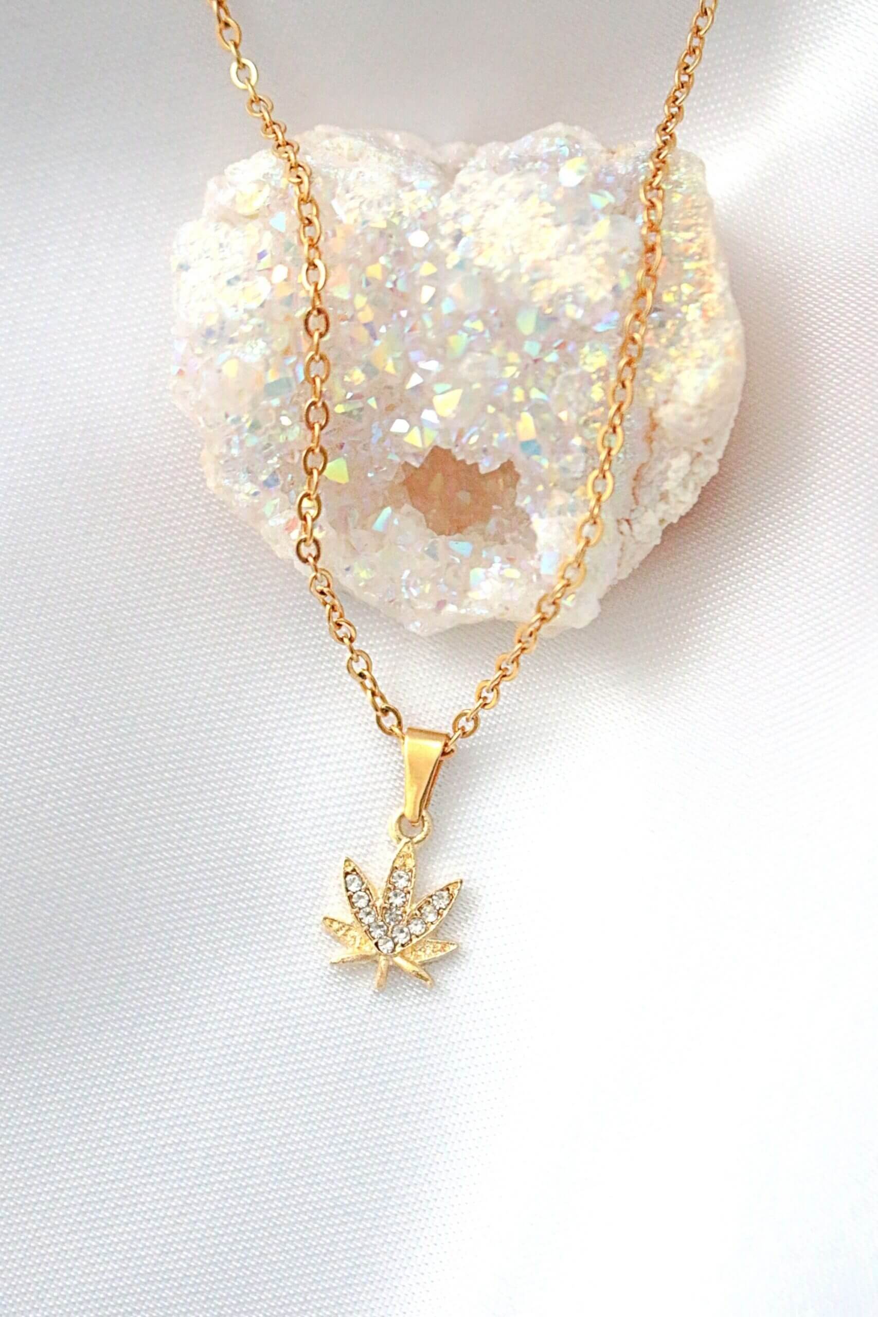 Gold necklace with a leaf pendant on a white background