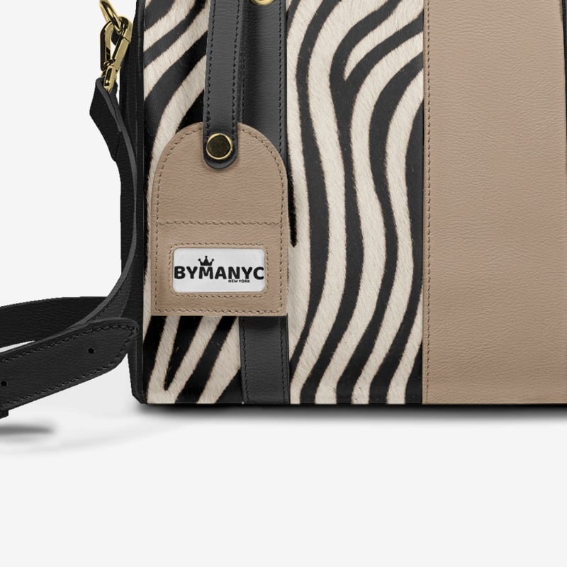 Handbag with zebra pattern and beige accents, featuring the brand 'Bymanyc'.