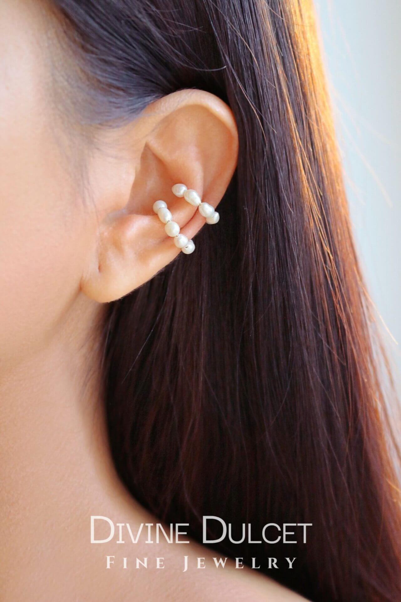 Close-up of an ear wearing a pearl earring with 'Divine Dulcet Fine Jewelry' branding.