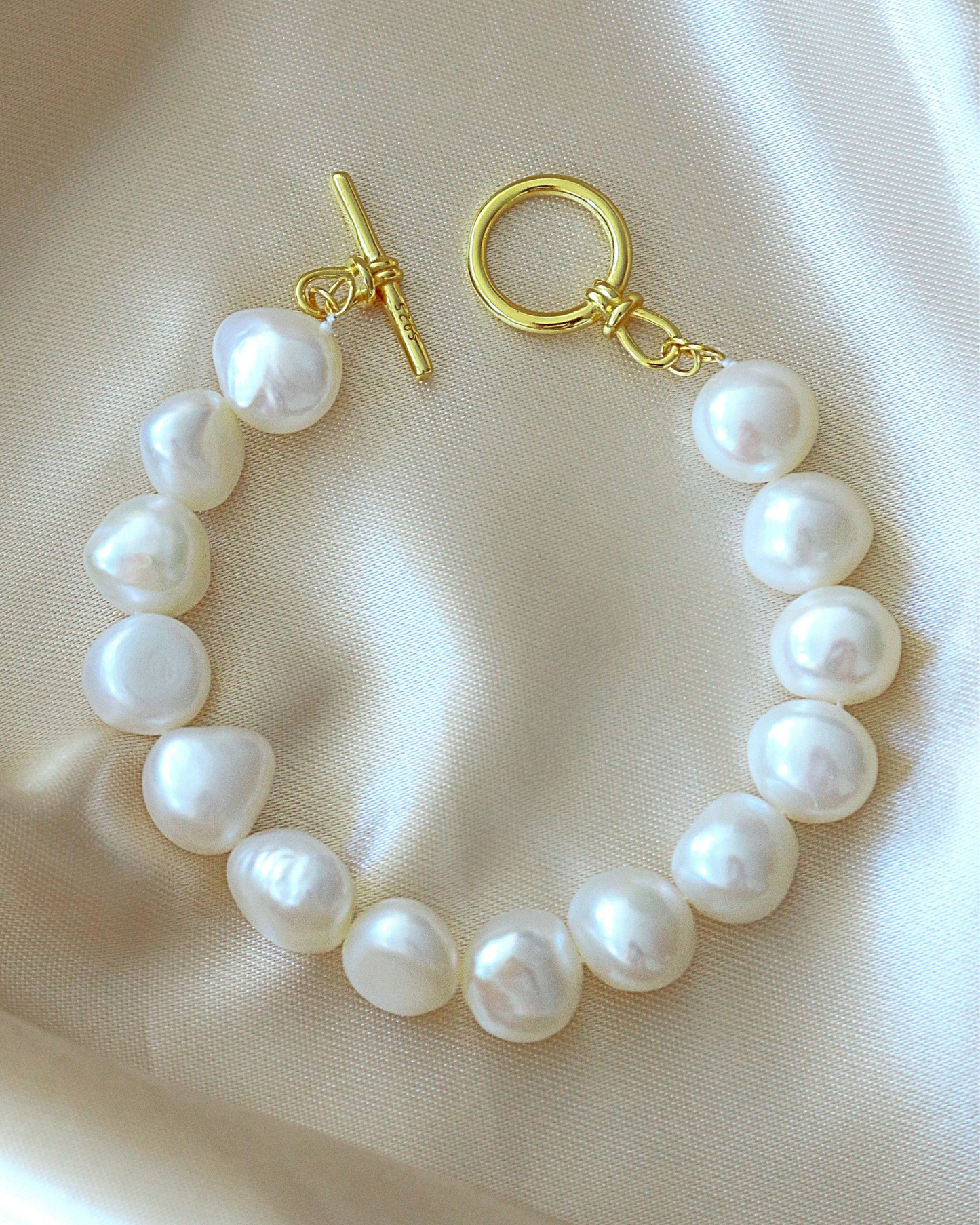 Pearl bracelet with gold clasp on a beige fabric background