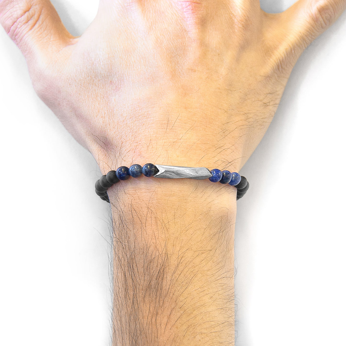 Hand wearing a black beaded bracelet with a silver bar on a white background