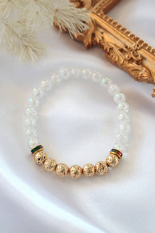 Bracelet with gold and white beads on a white surface with decorative elements.