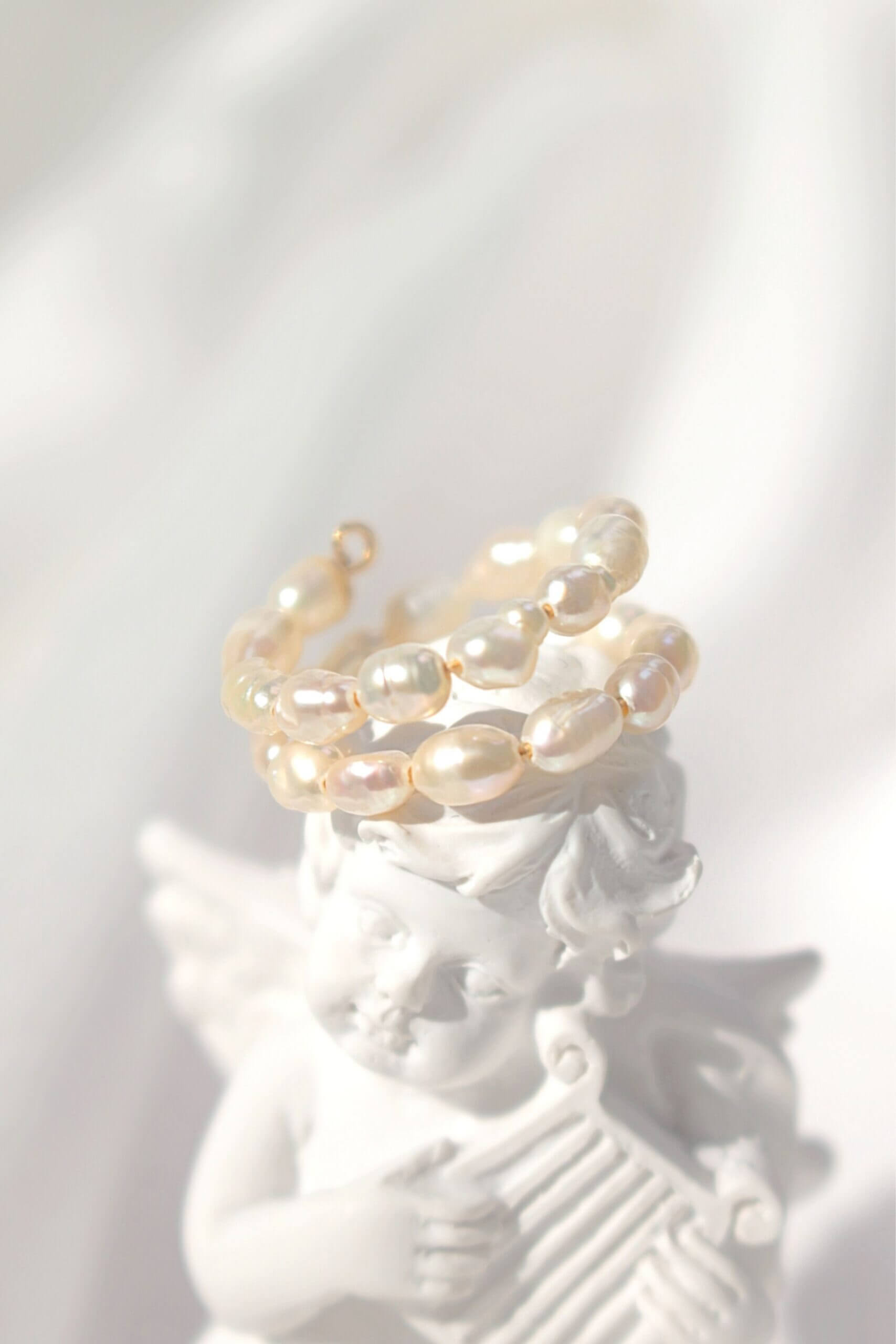 Pearl ring on a white ceramic figure with a soft focus background