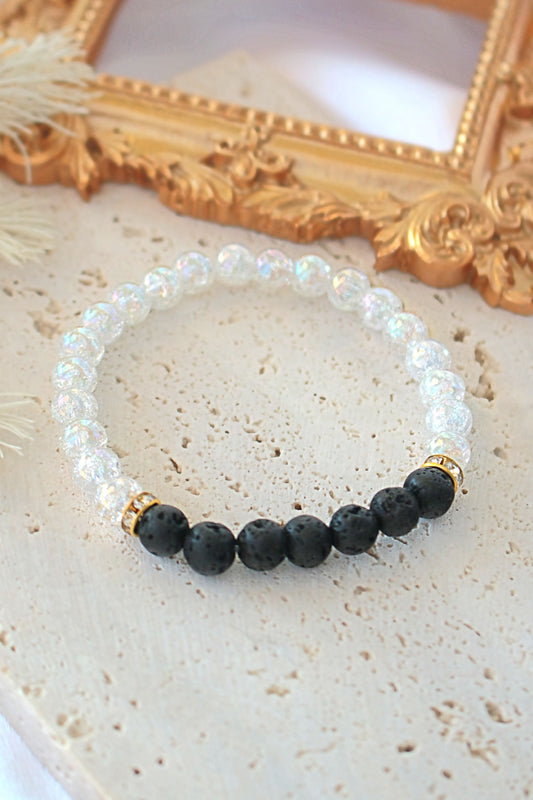 Beaded bracelet with black and white beads on a textured surface with a gold frame in the background.