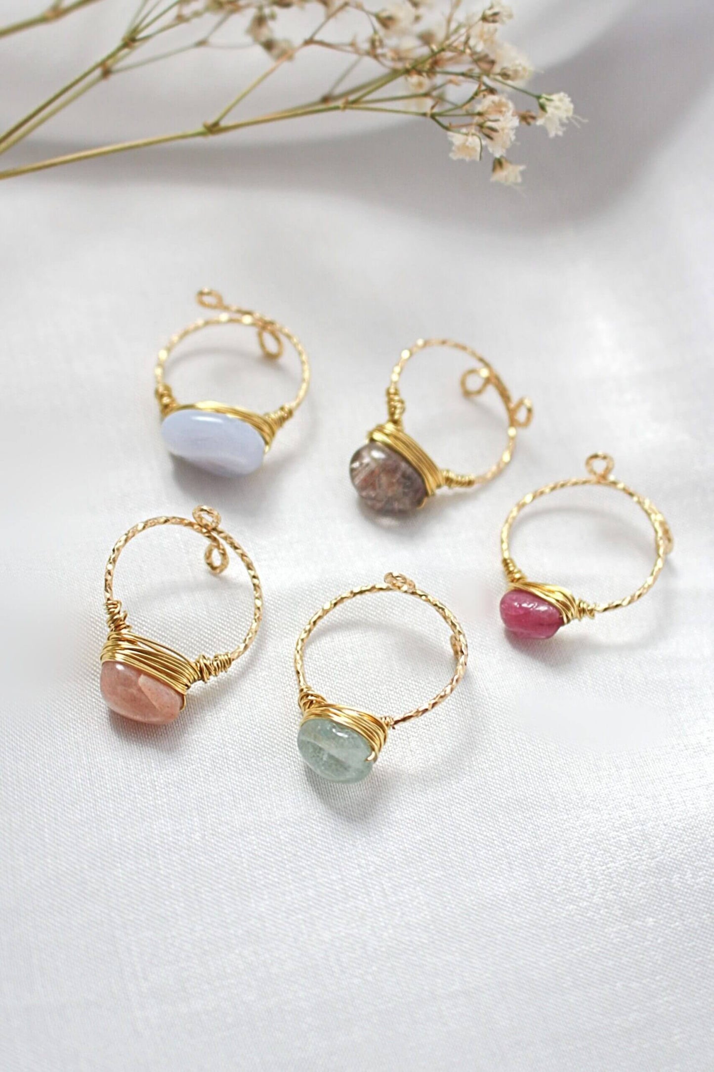 Gold hoop earrings with various colored stones on a light background