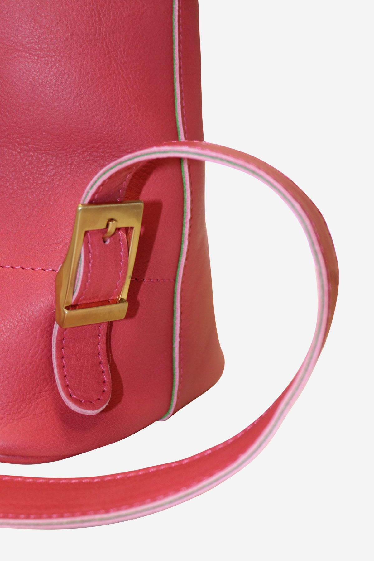 Close-up of a pink handbag with a gold buckle and white strap on a light gray background