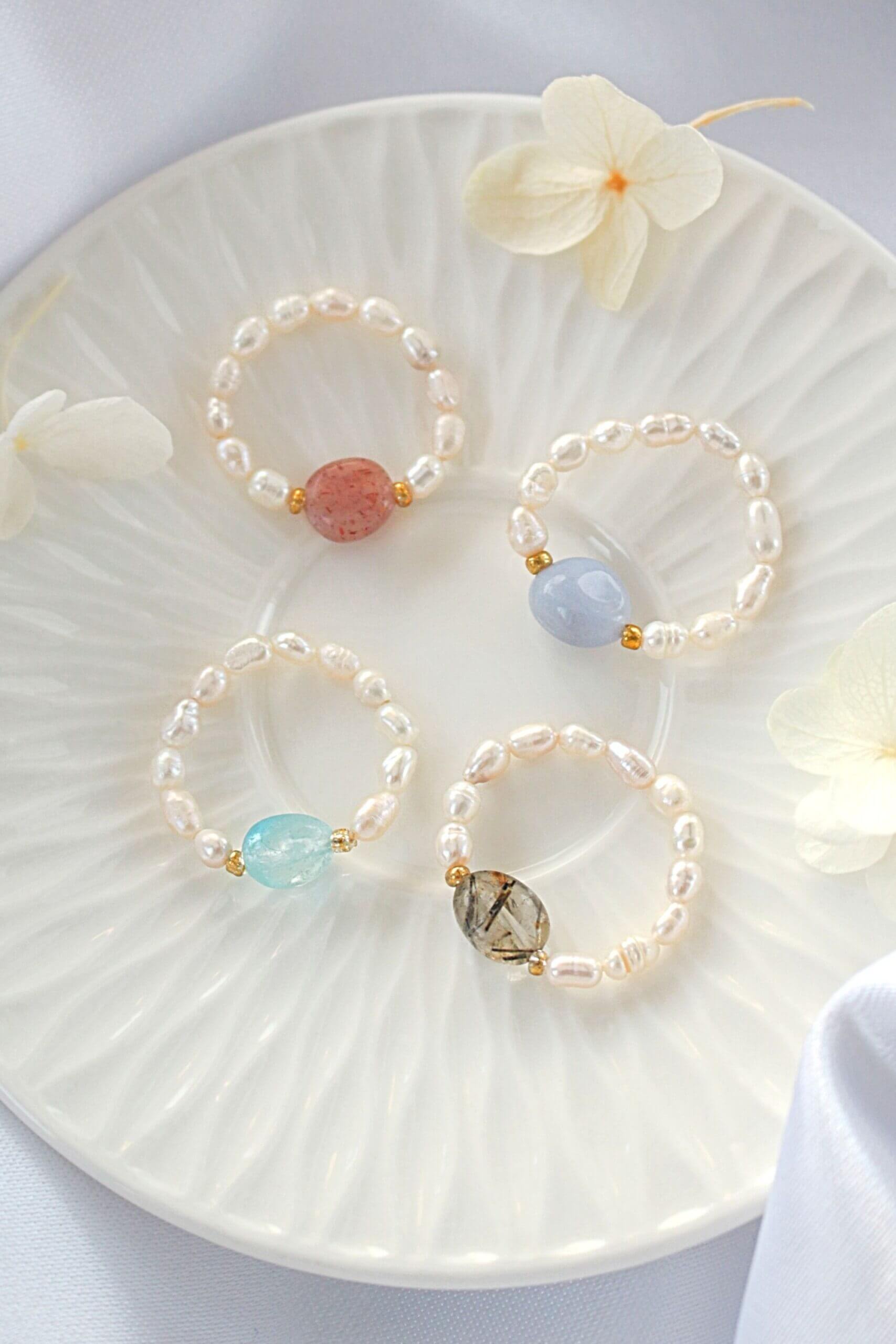 Three pearl bracelets with colorful beads on a white plate with flowers