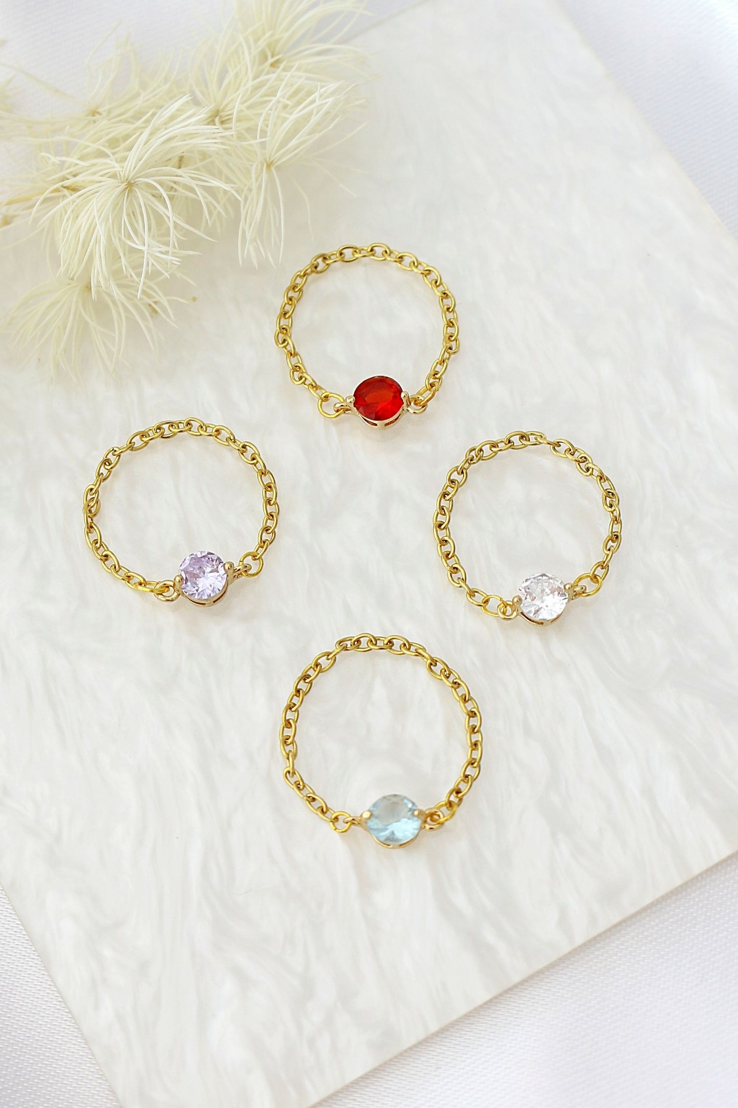 Set of gold rings with colorful gemstones on a white fabric background