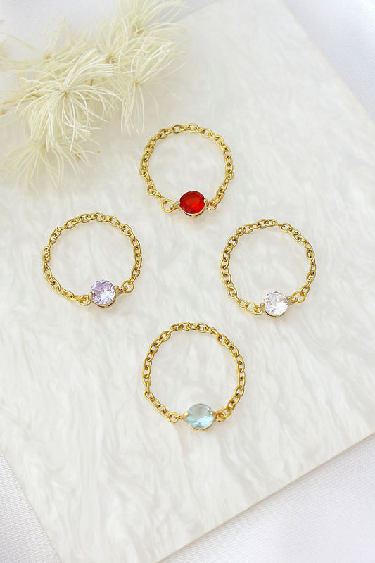 Set of gold rings with colorful gemstones on a white fabric background