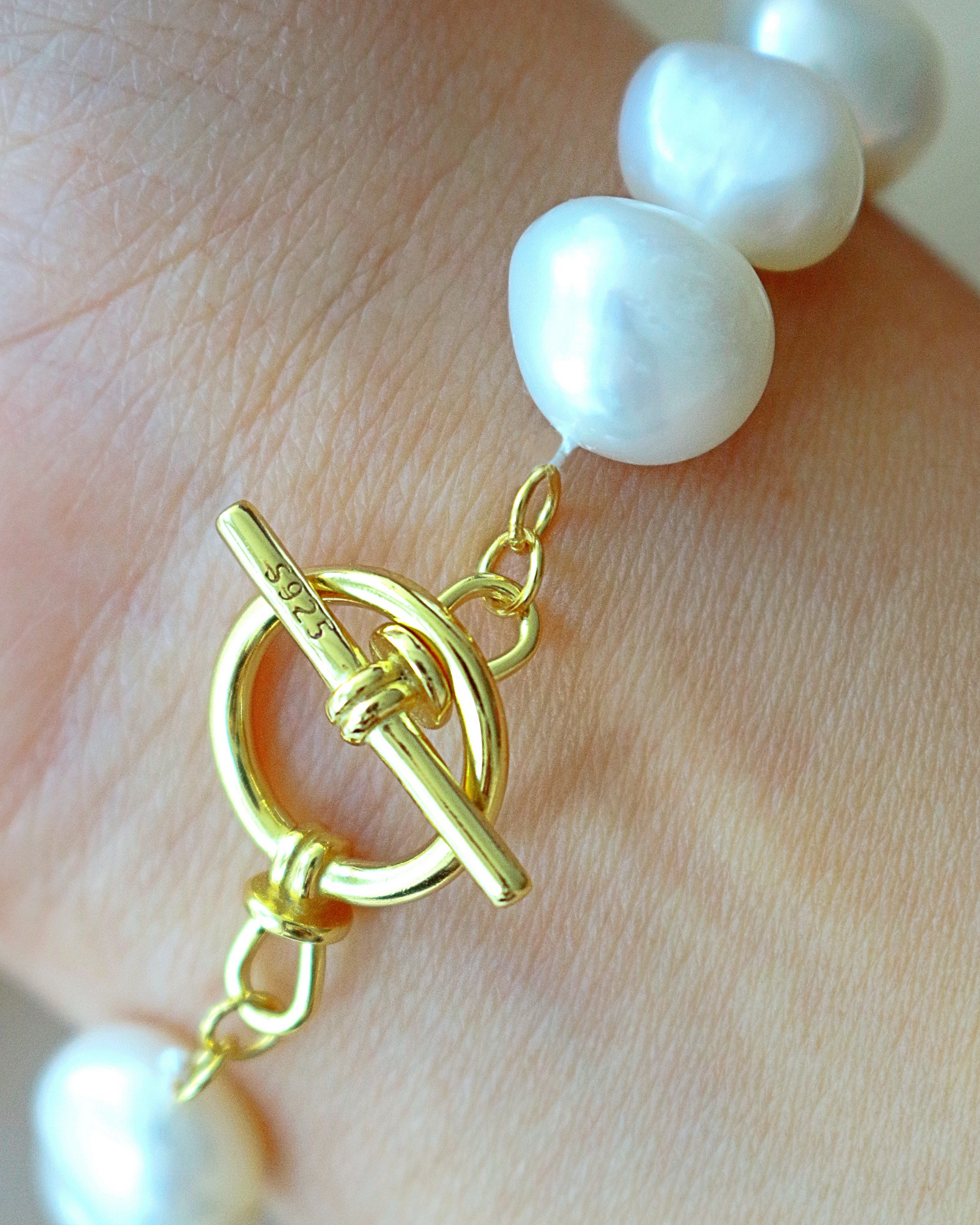 Pearl bracelet with a gold clasp on a hand