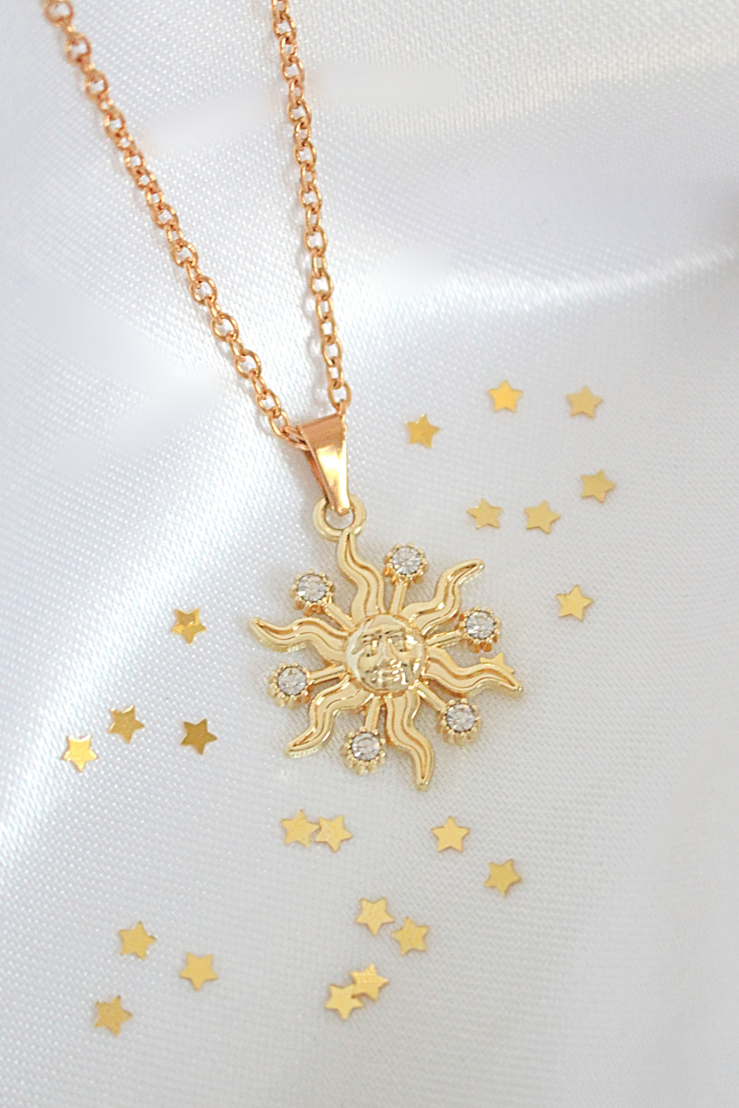 Gold sun-shaped pendant necklace on a white background with gold stars