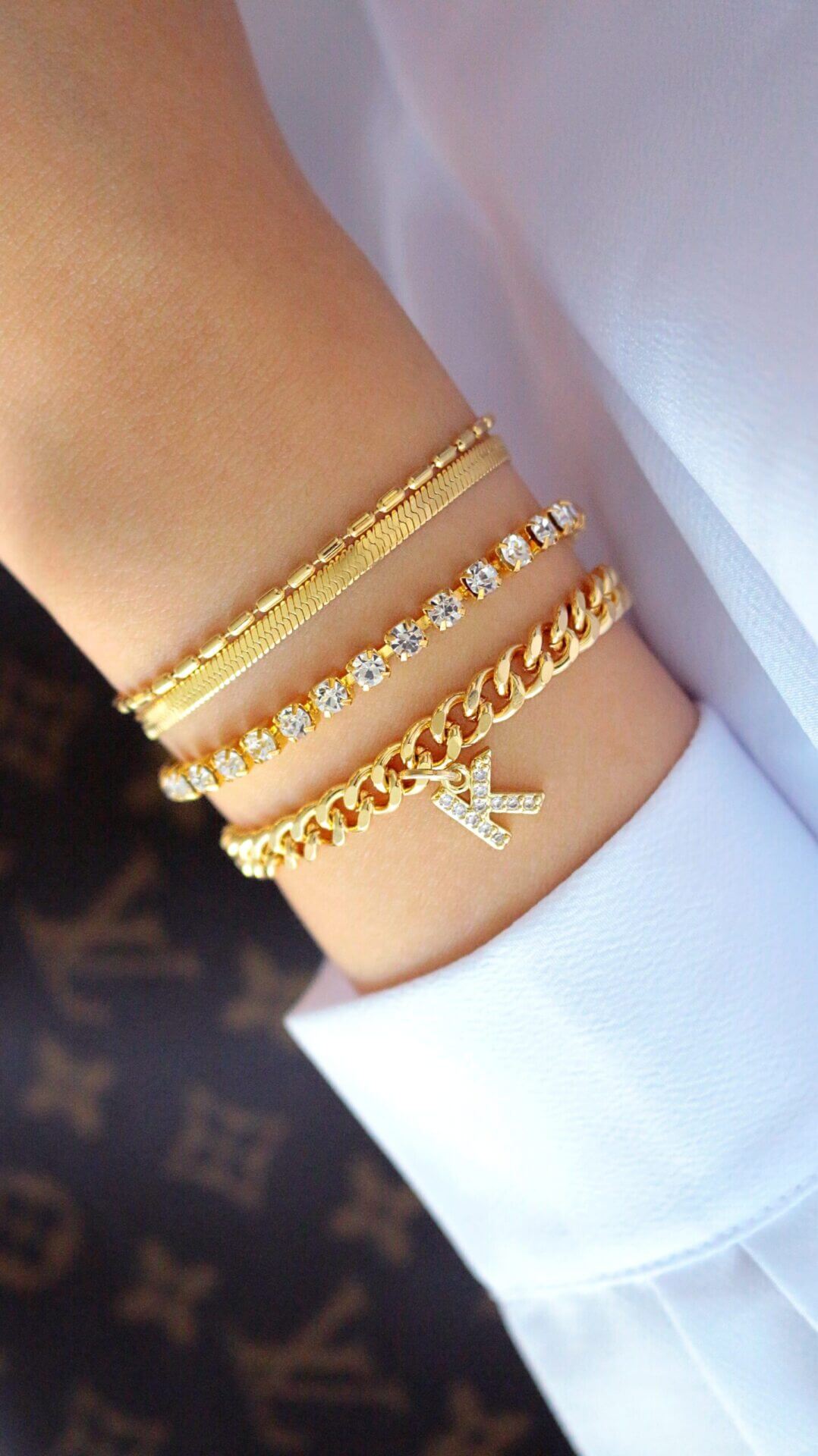 Gold bracelets on a wrist with a white background