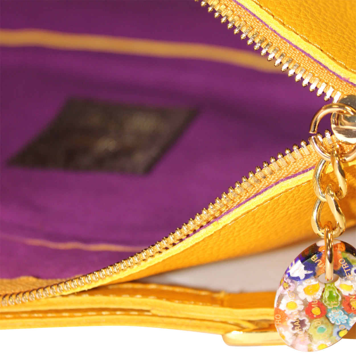 Close-up of a yellow zipper with a colorful charm on a purple background