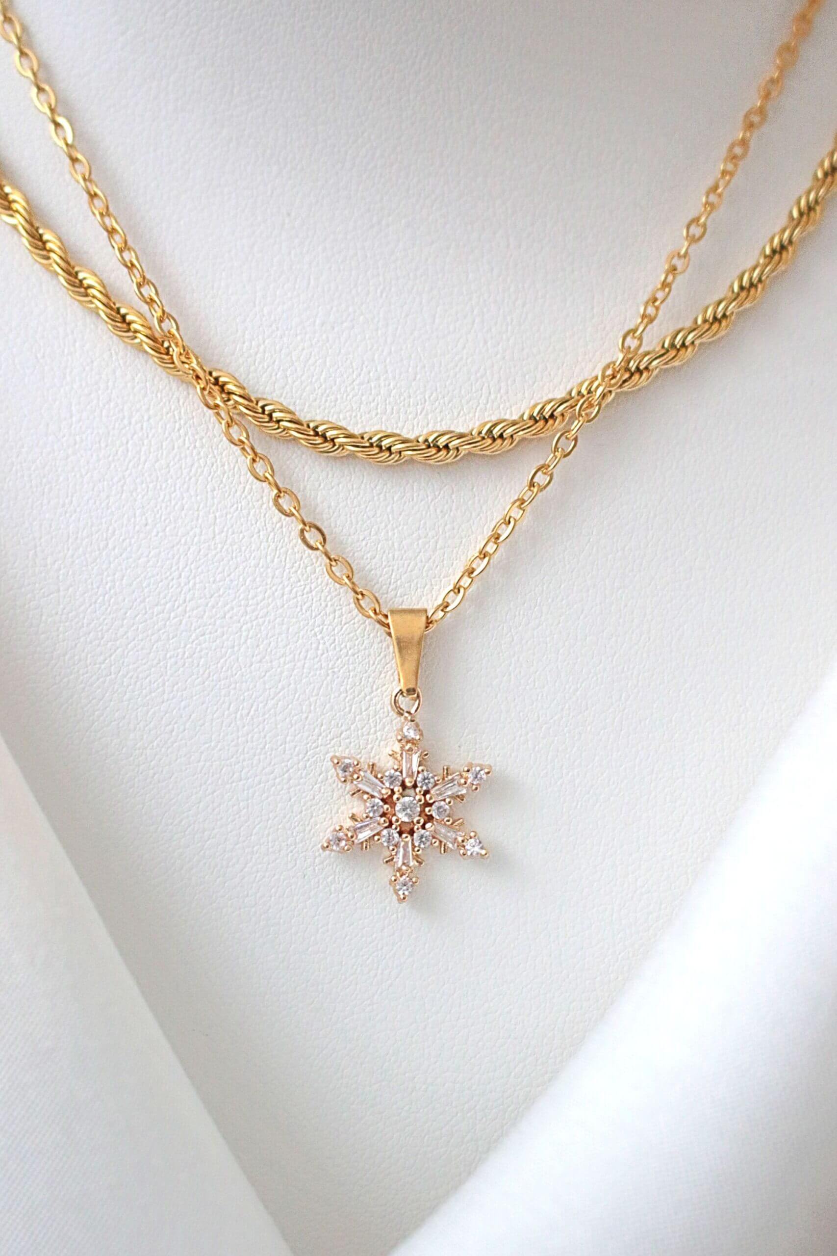 Gold necklace with a star-shaped pendant on a white background