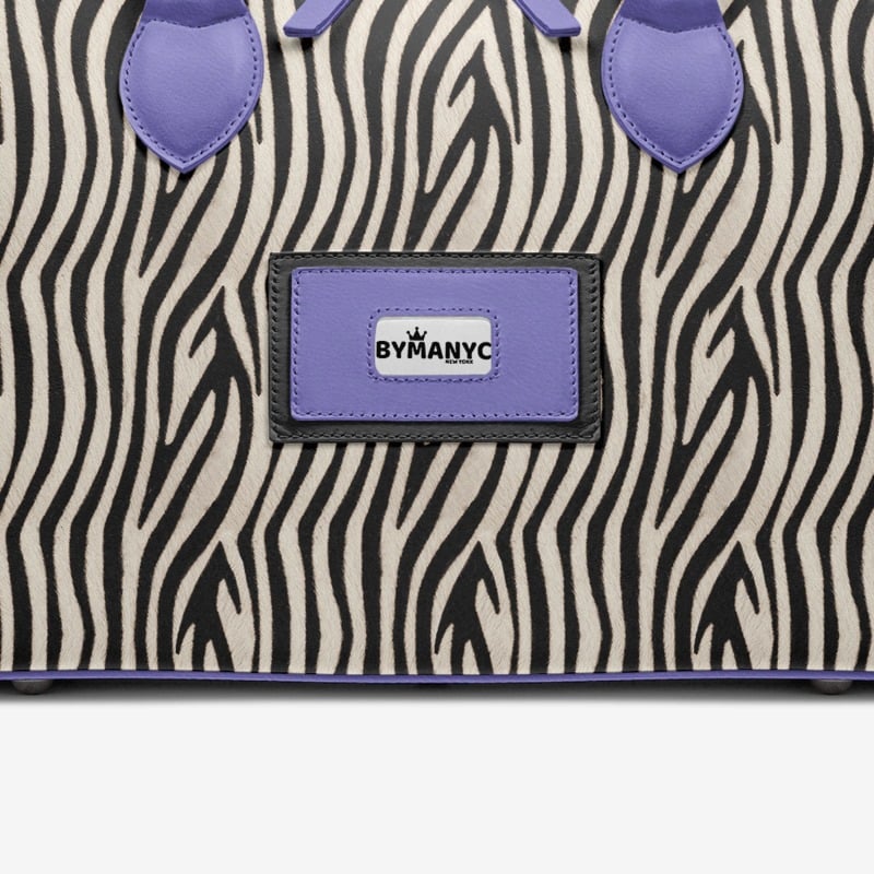 Zebra-patterned bag with purple accents and a ByManyC label on a white background