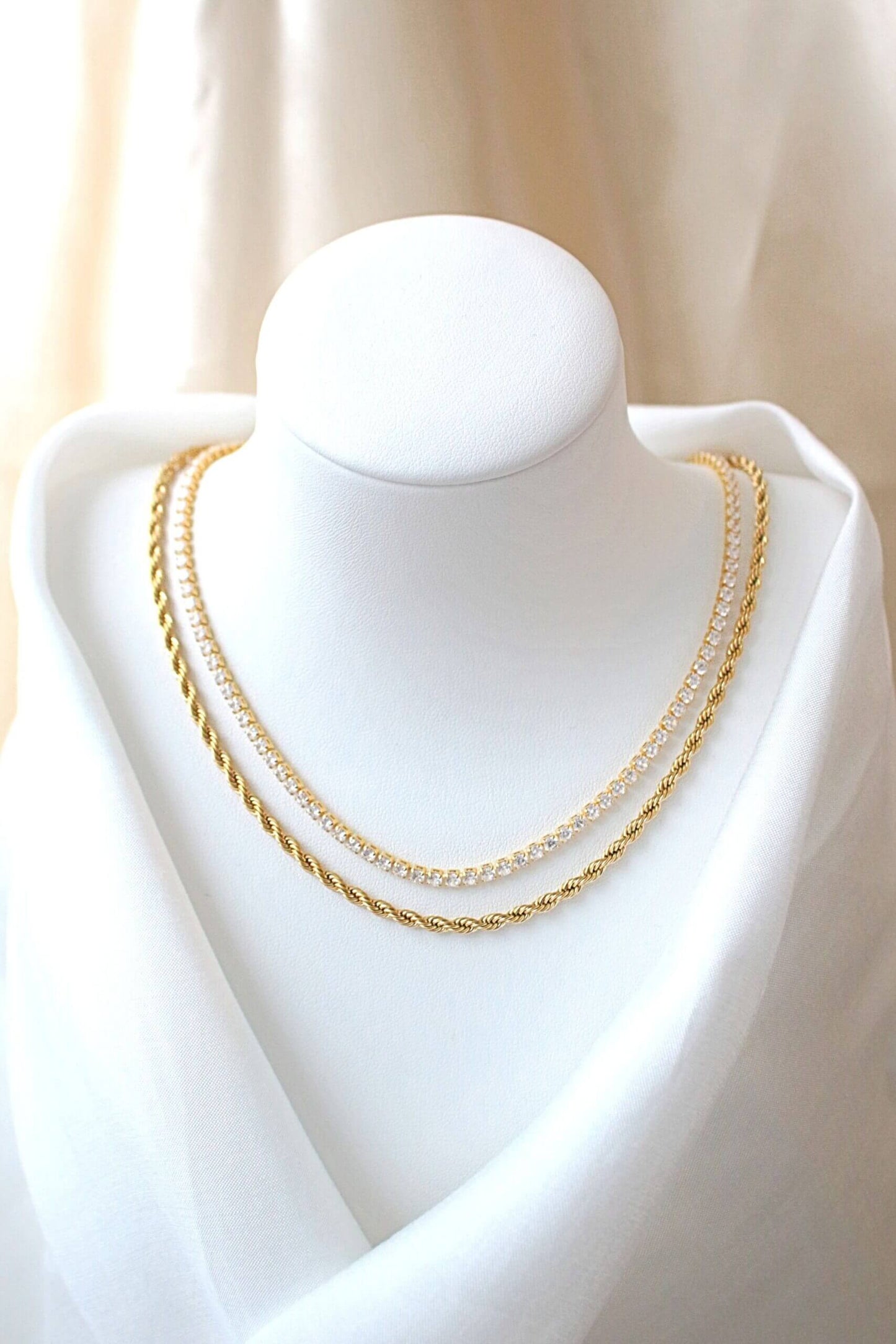 Gold chain necklace on a mannequin bust against a neutral background