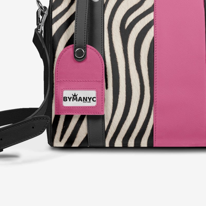 Handbag with zebra pattern and pink section, featuring a 'Bymanyc' tag.