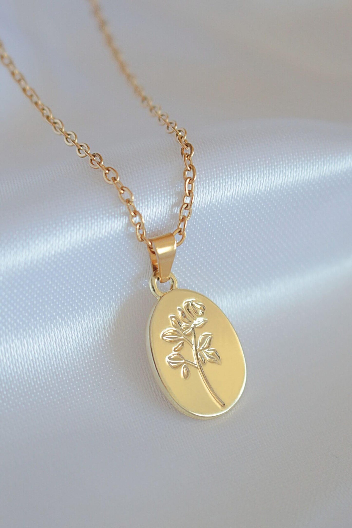Gold necklace with a pendant on a white satin background