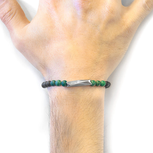Green beaded bracelet on a wrist with a white background