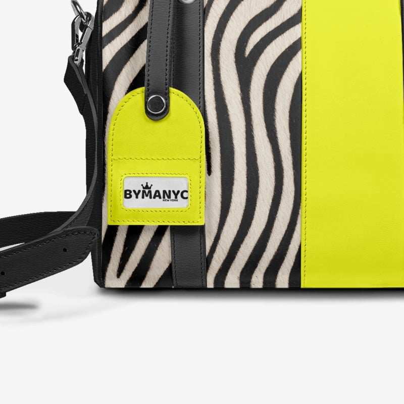 Handbag with zebra pattern and yellow accent, featuring ByManyC brand label.