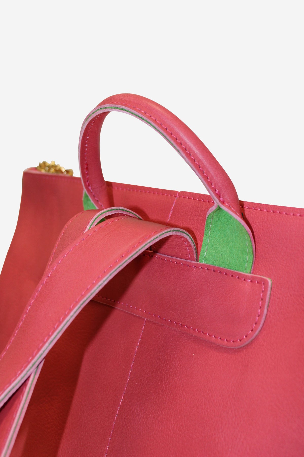 Close-up of a red handbag with green interior lining on a light pink background