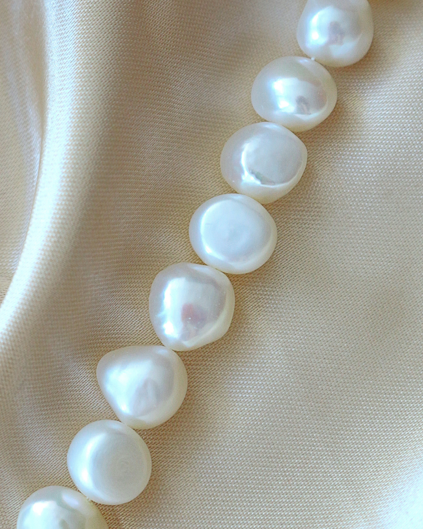 Pearl necklace on a beige fabric background