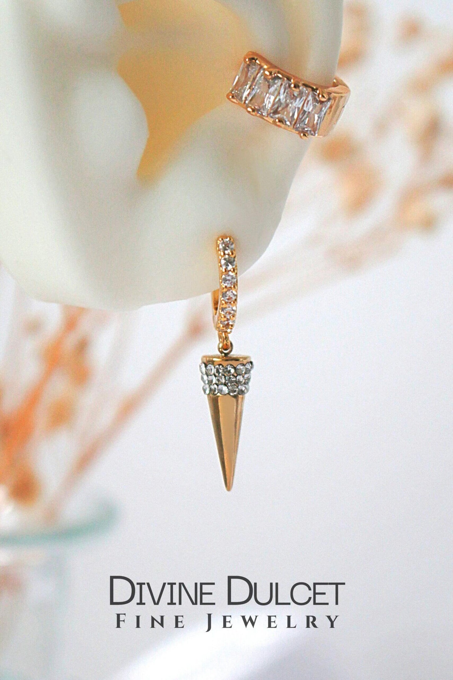 Gold earrings with diamond accents on a blurred background, featuring the brand 'Divine Dulcet'.