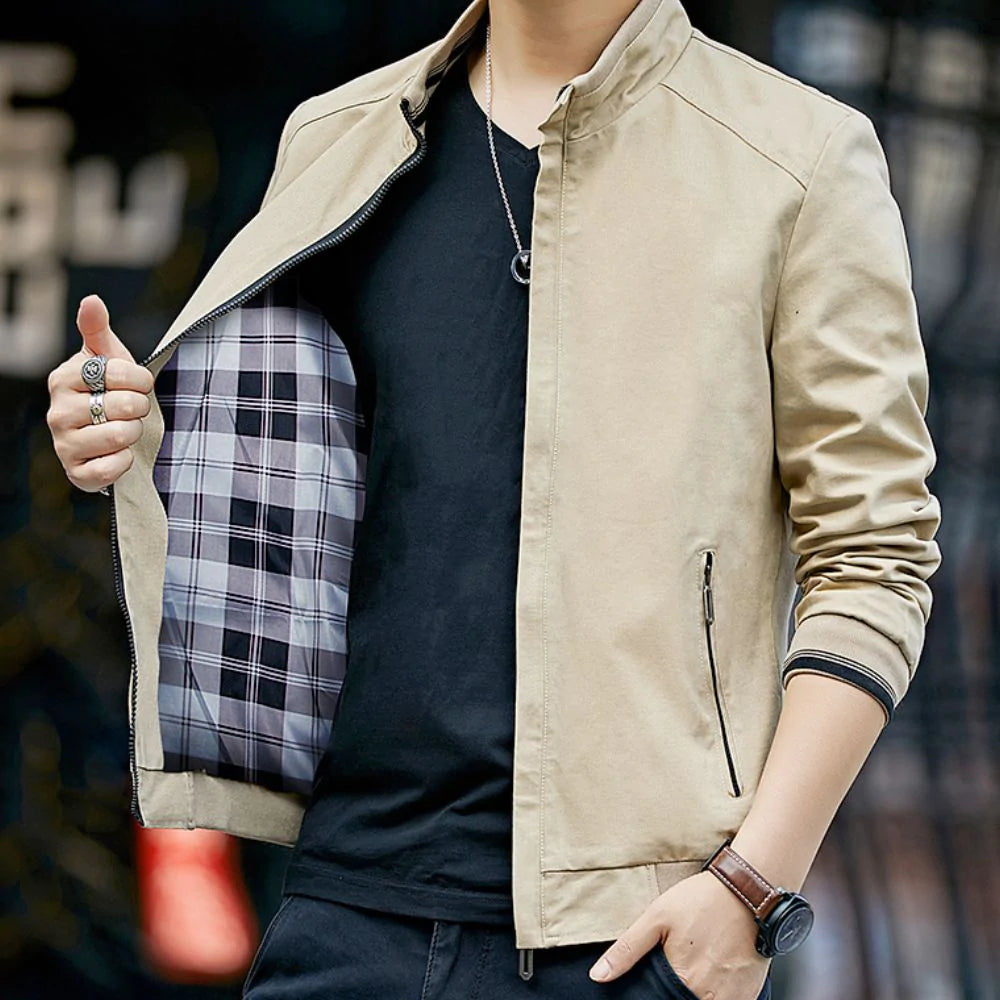 Person wearing a beige jacket with plaid lining, standing against a blurred background.