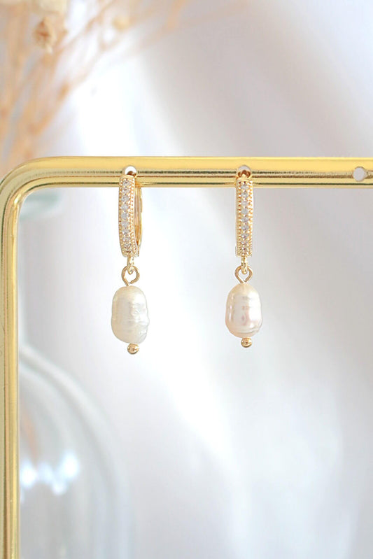 Pearl earrings on a gold stand with a soft white background