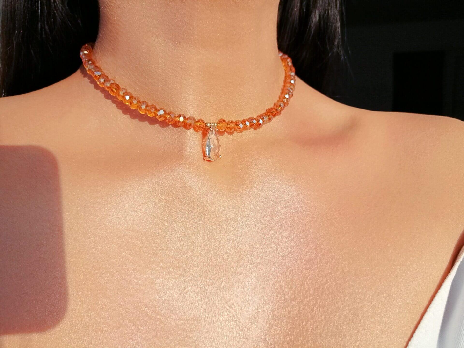 Close-up of a person wearing an orange beaded necklace against a neutral background