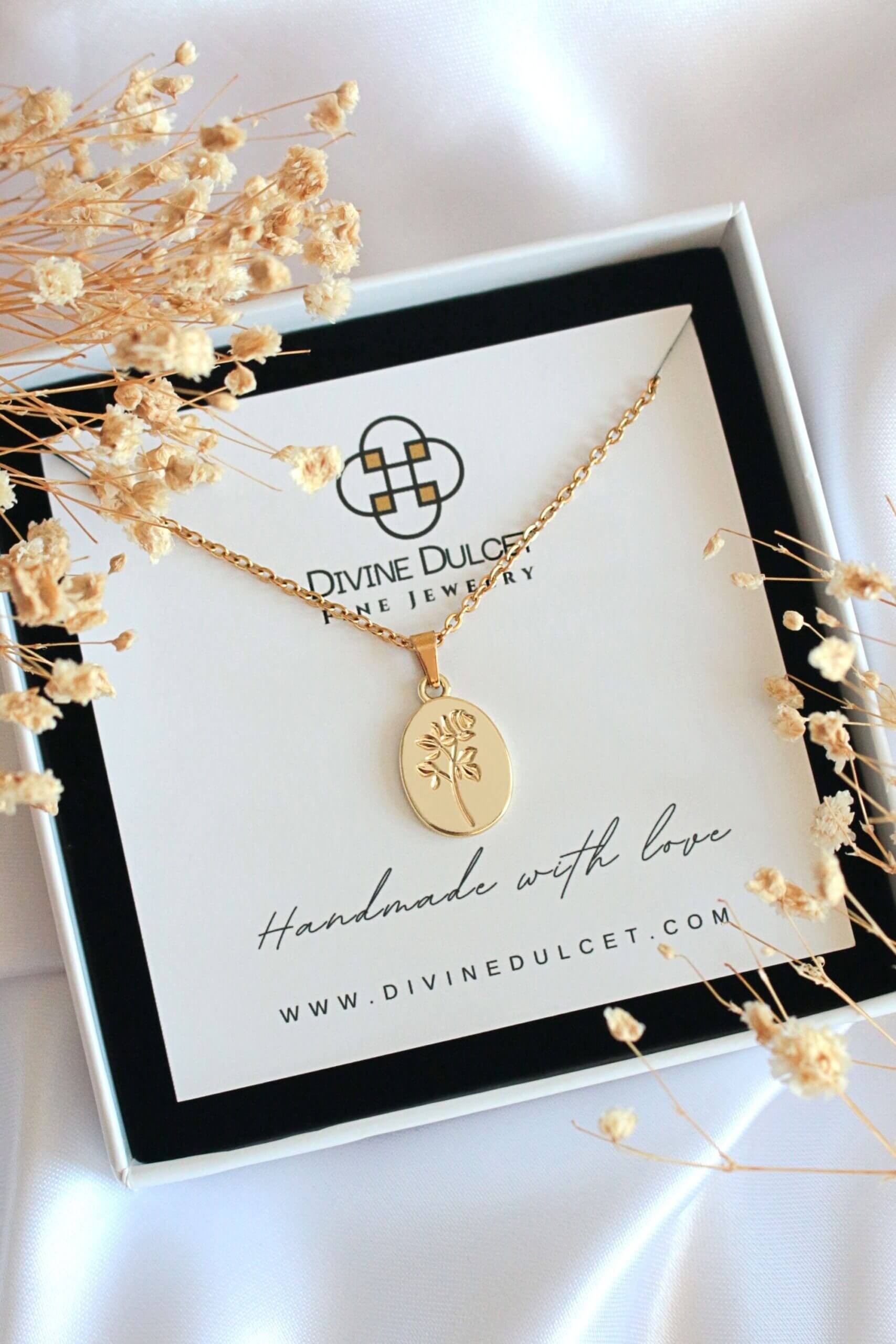 Gold necklace on a card with 'Divine Dulcet' branding, surrounded by dried flowers.