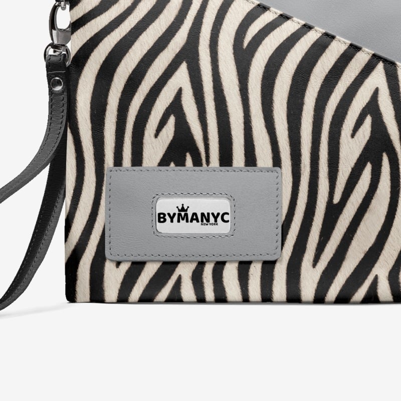Zebra patterned handbag with a gray patch displaying 'BY MANYC' on a light gray background