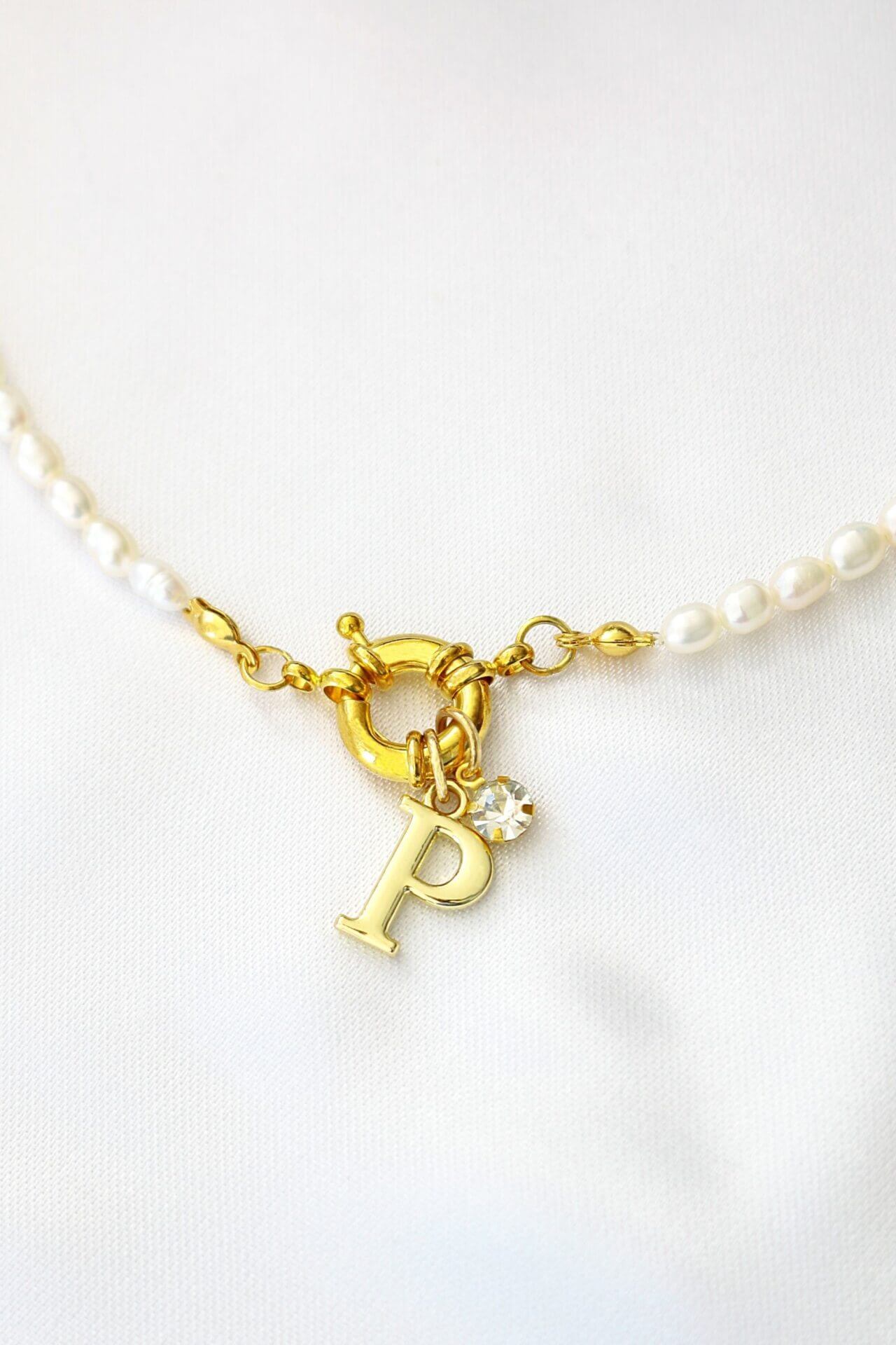 Gold necklace with a letter 'P' charm on a white background