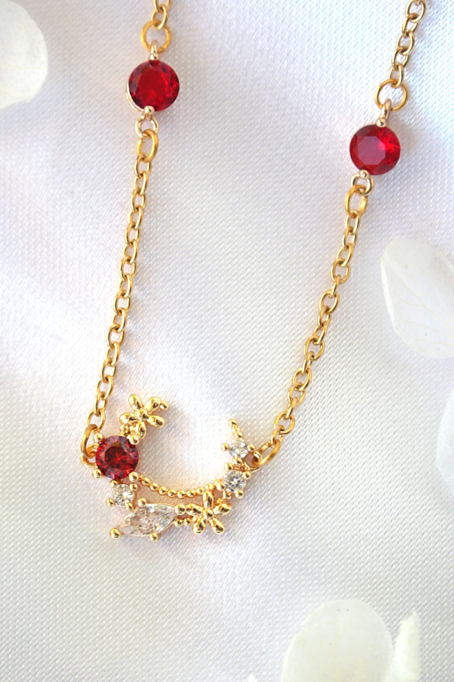 Gold necklace with red beads on a white background