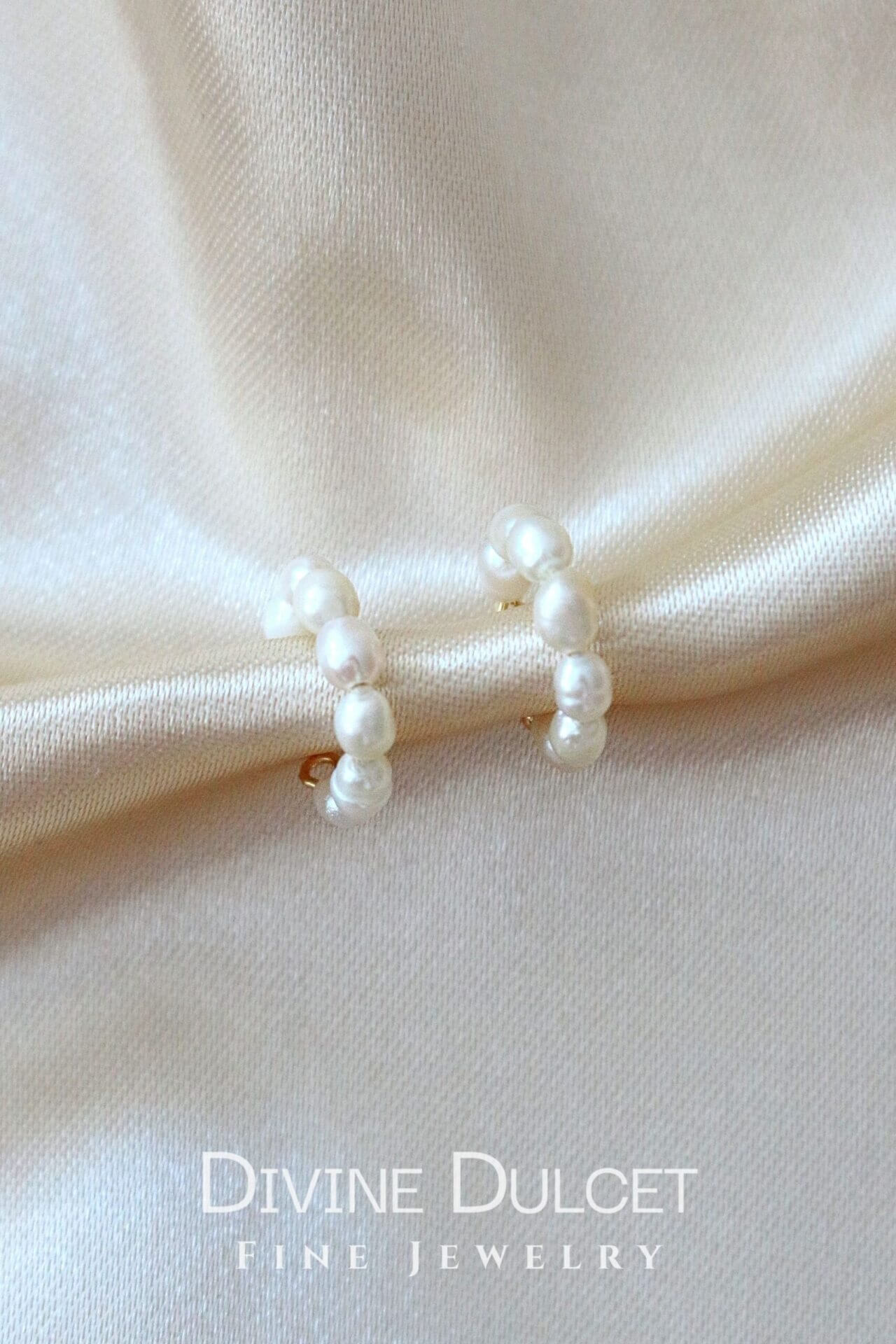 Pearl earrings on a beige fabric background with 'Divine Dulcet Fine Jewelry' branding.